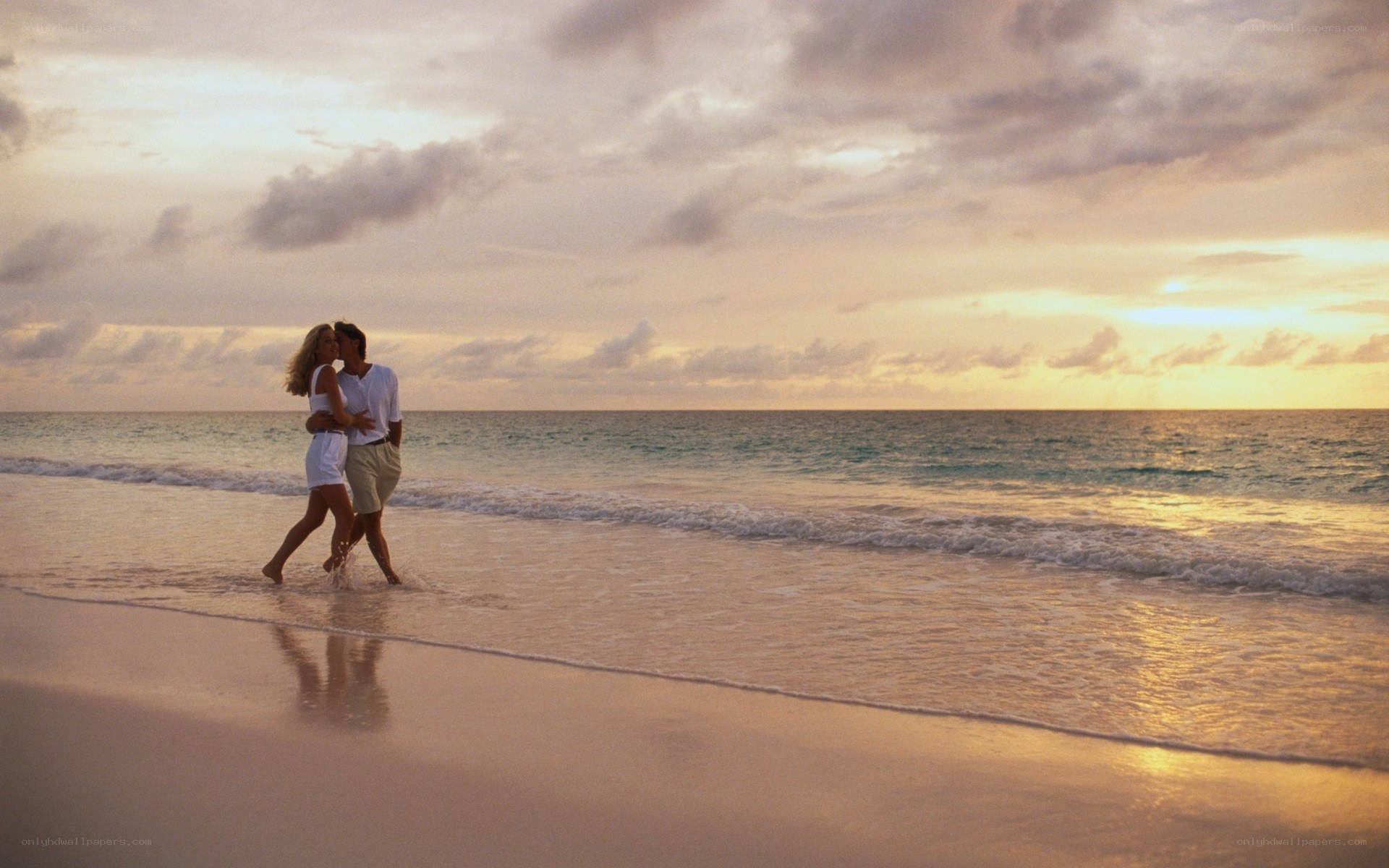 Couple walking on beach at sunset