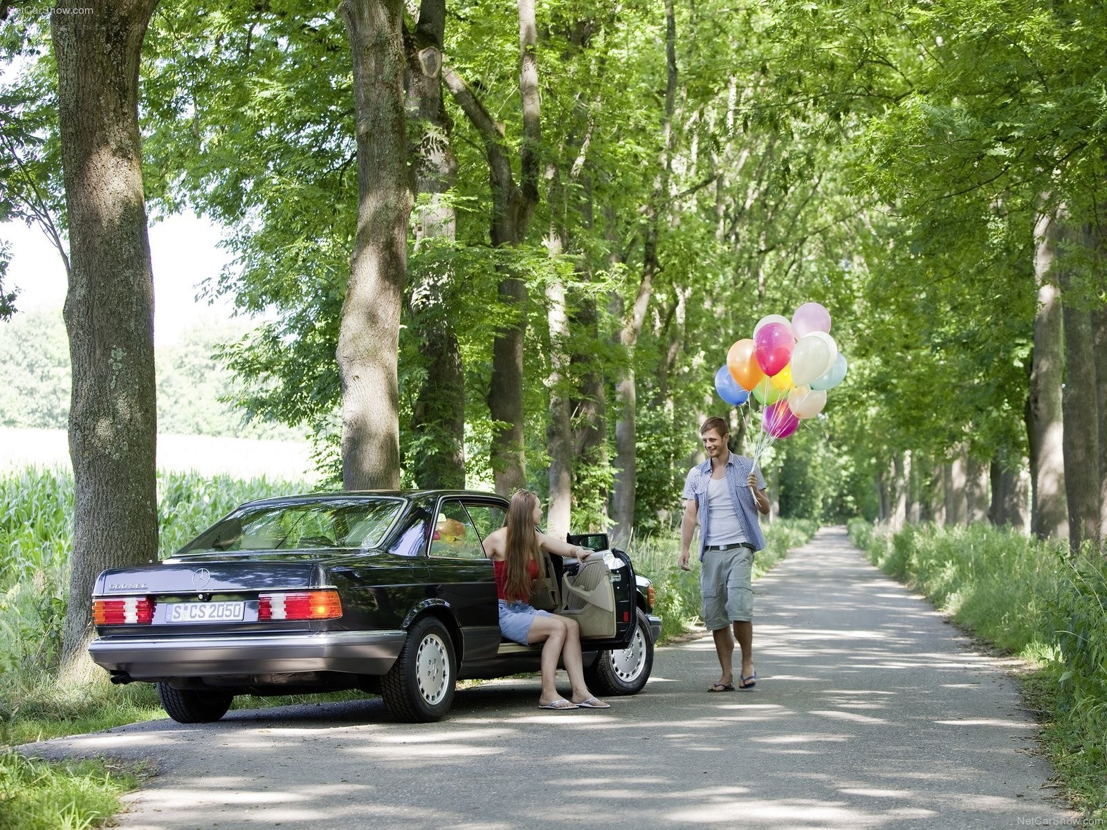 Couple with balloons by car