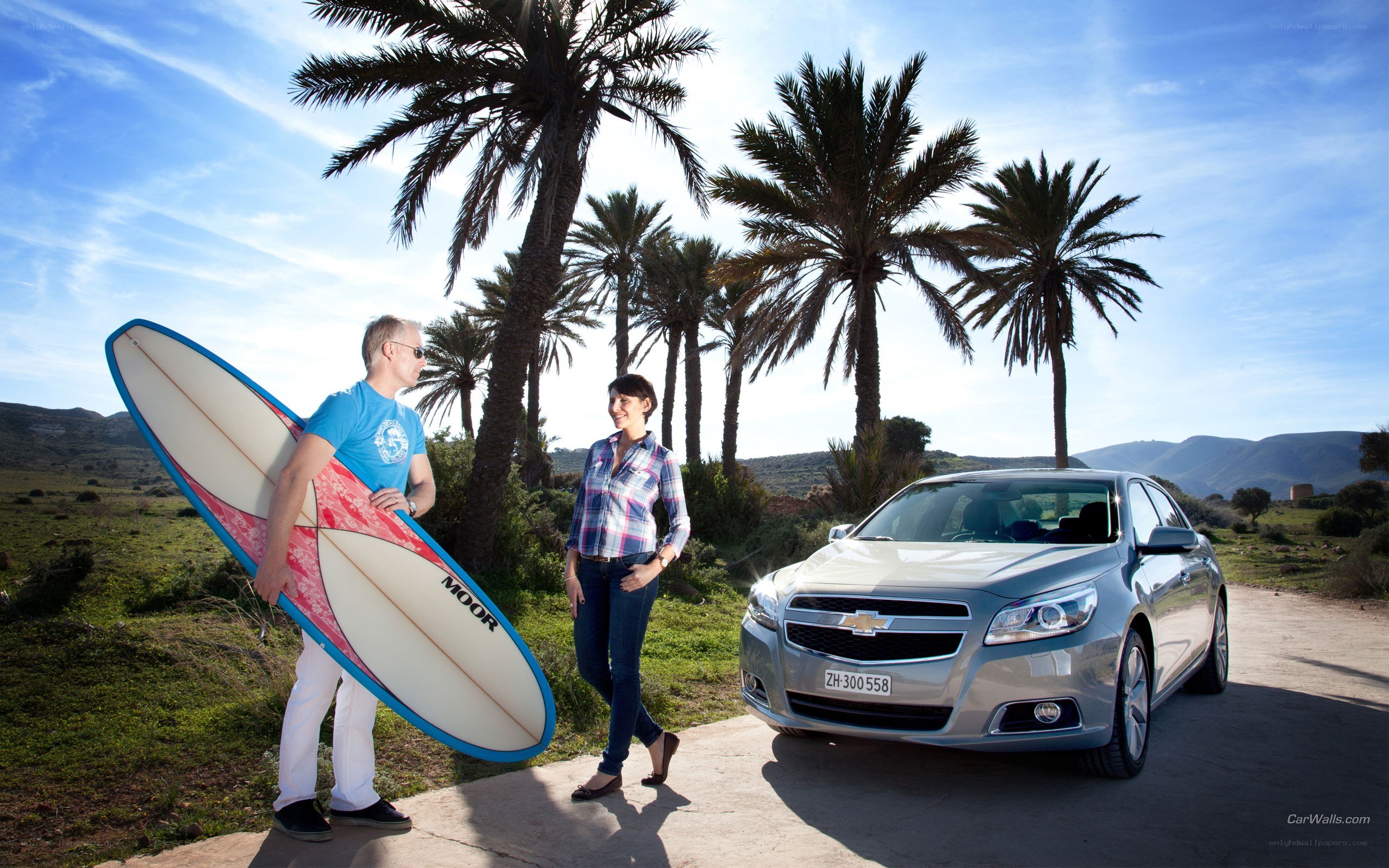 Couple with surfboard and car