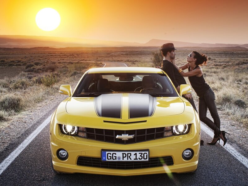 Couple with yellow car at sunset