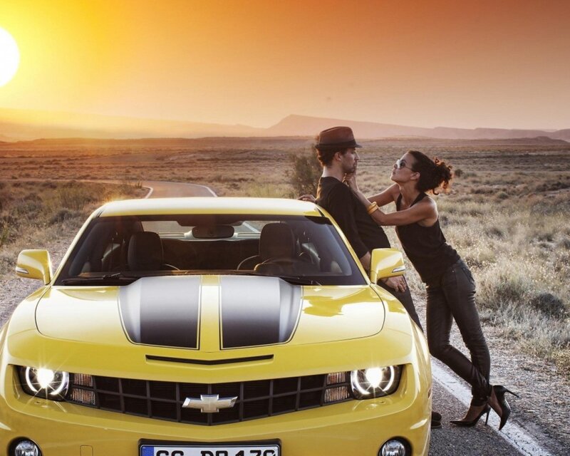 Couple with yellow car at sunset