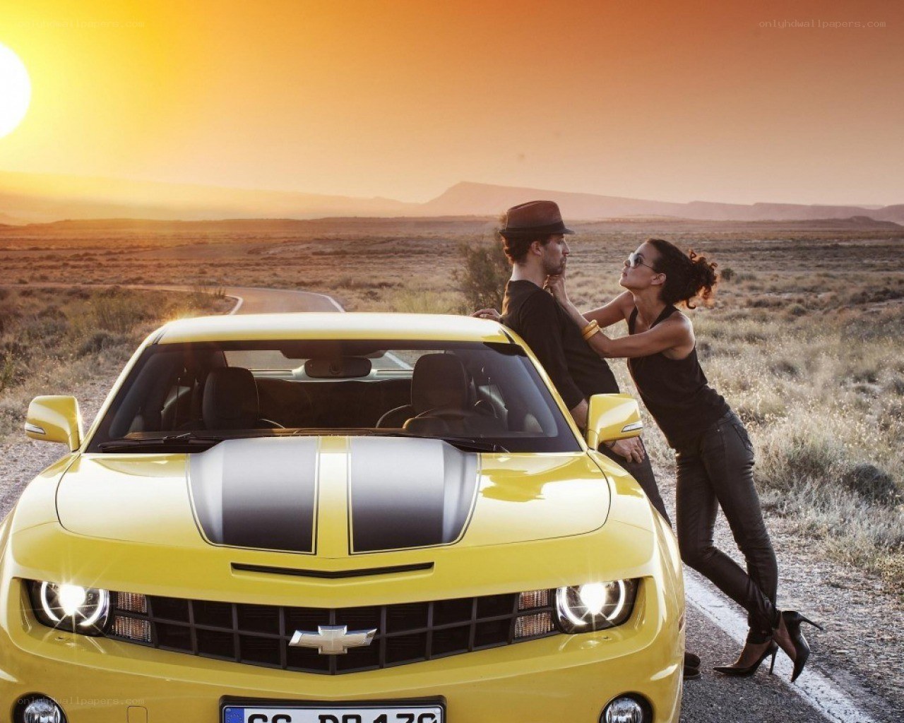 Couple with yellow car at sunset