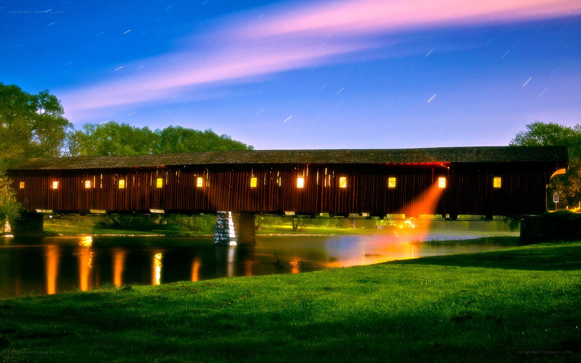 Covered bridge at night with star trails