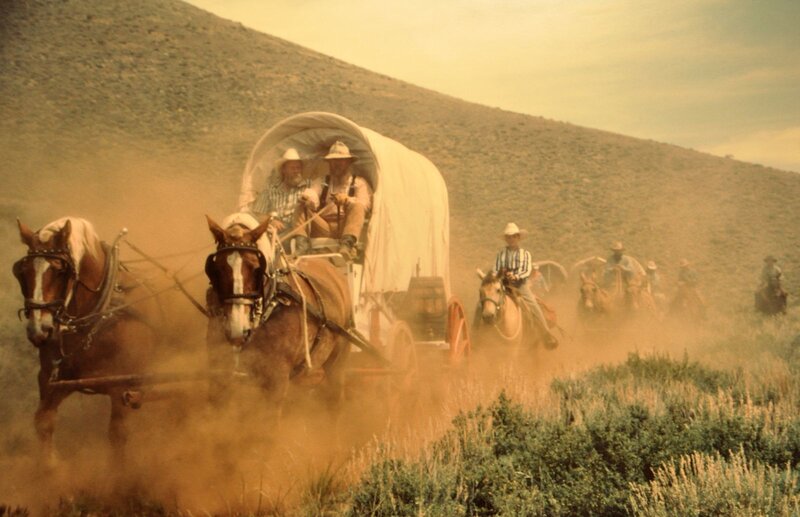 Covered wagon train in dust