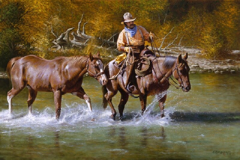 Cowboy crossing river with horses
