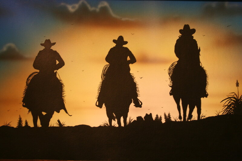 Cowboys on horseback at sunset