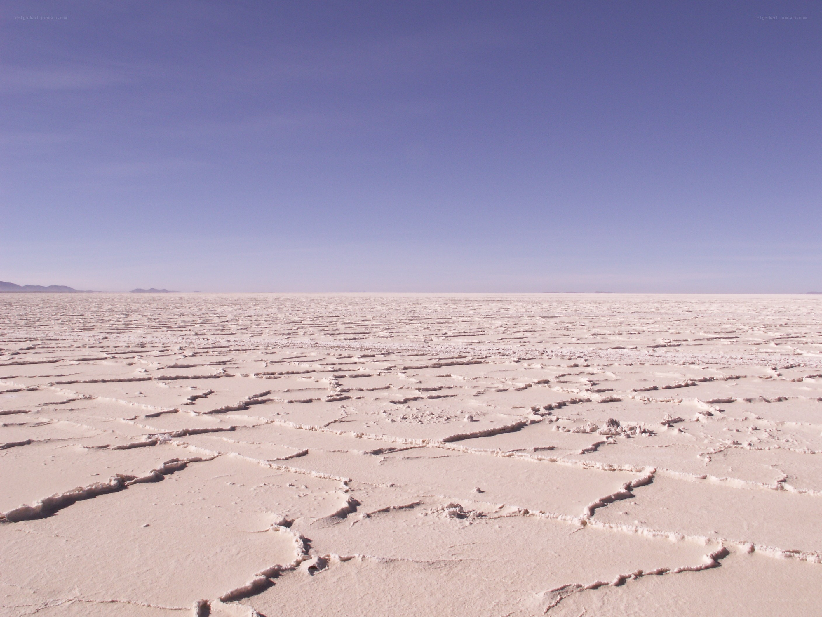 cracked salt flat under blue sky
