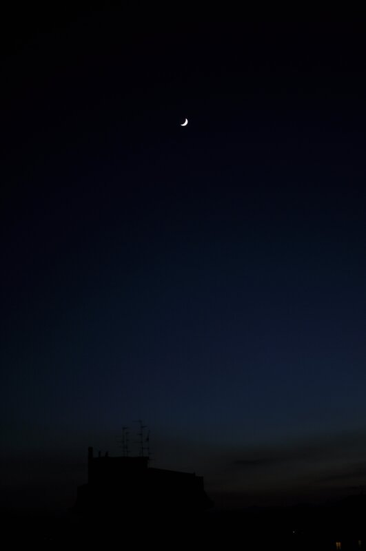 Crescent moon over city silhouette