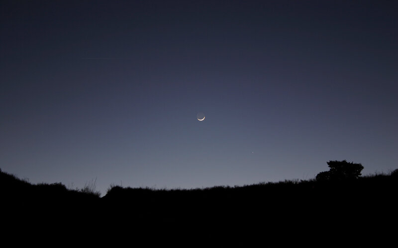 Crescent moon over hills