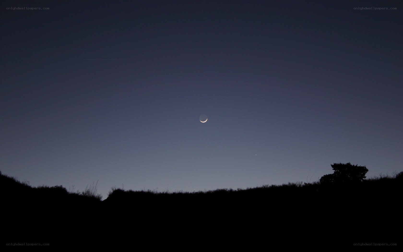 Crescent moon over hills