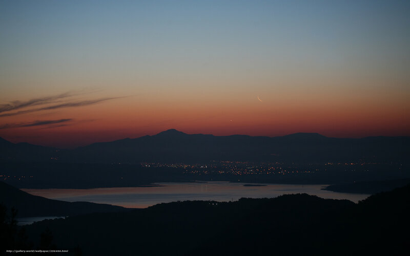 Crescent moon over lake at dusk