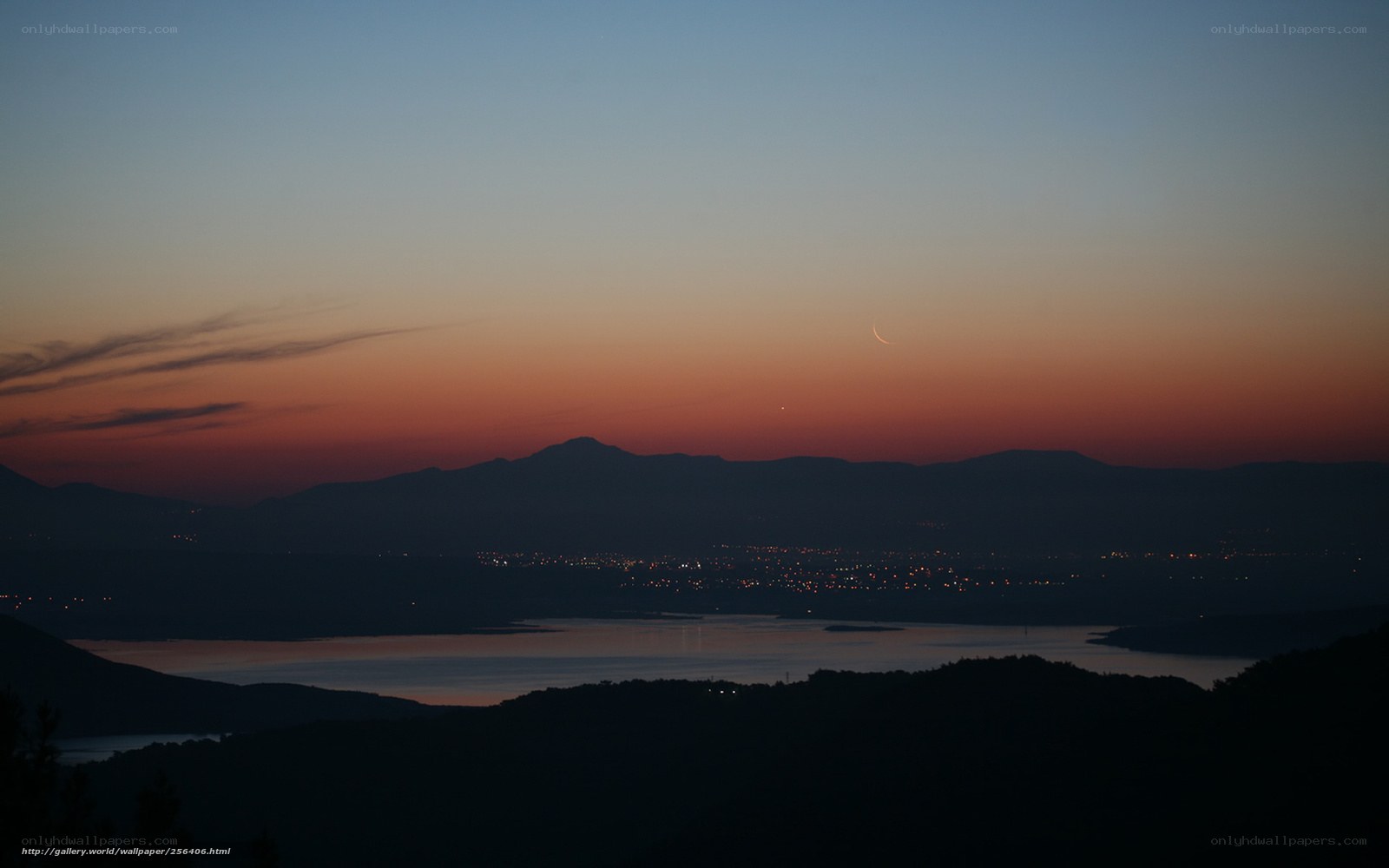 Crescent moon over lake at dusk