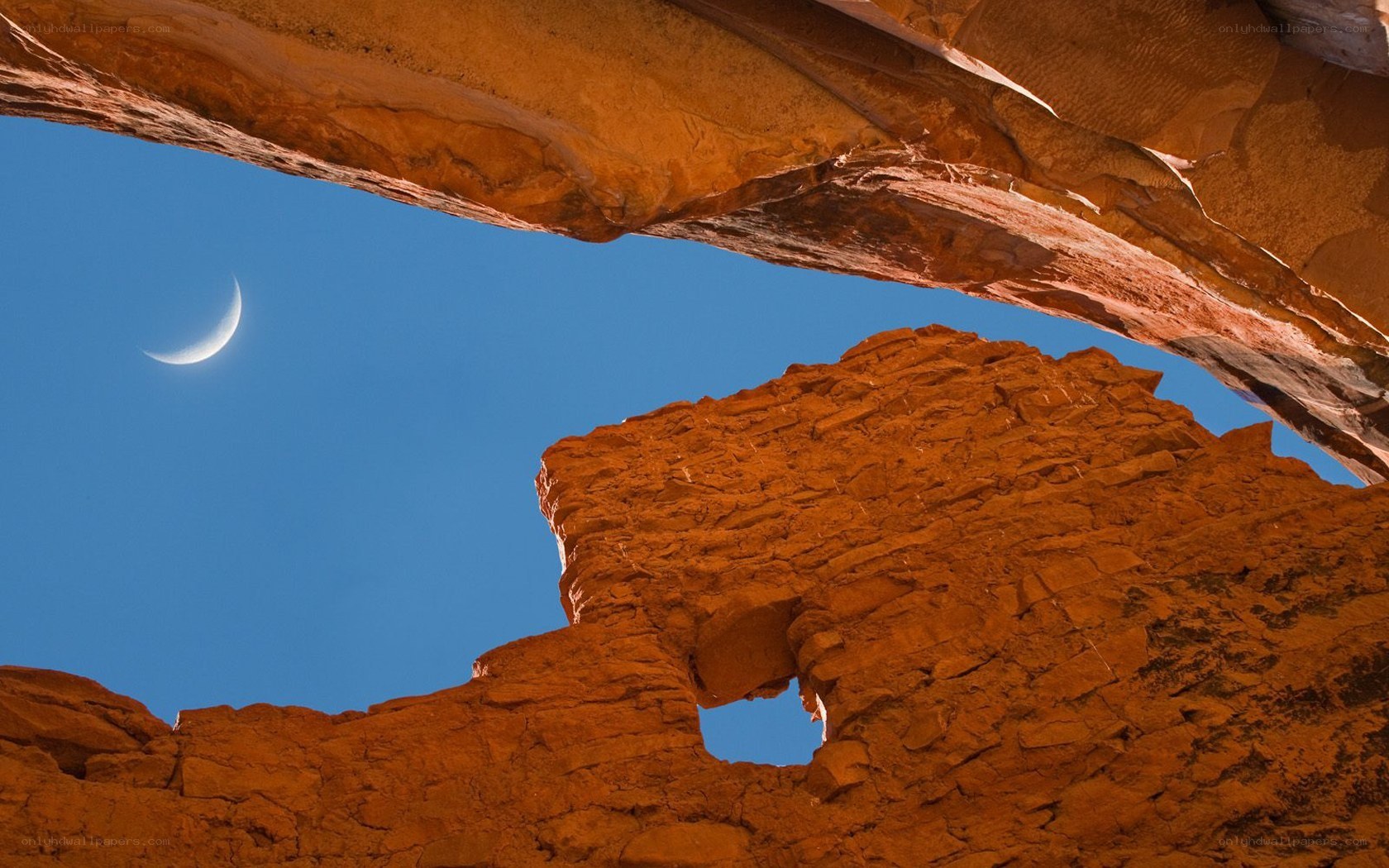 Crescent moon over red rock arch