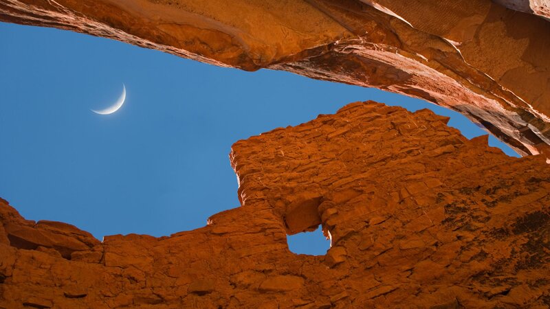 Crescent moon over rock arch