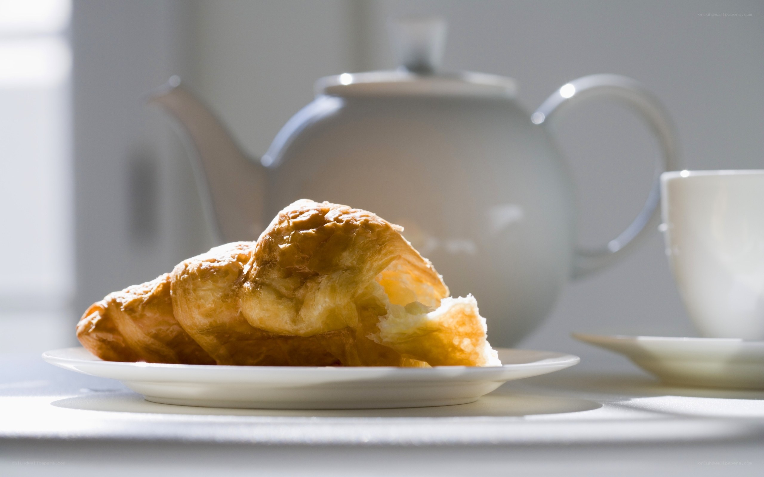 croissant and teapot on table