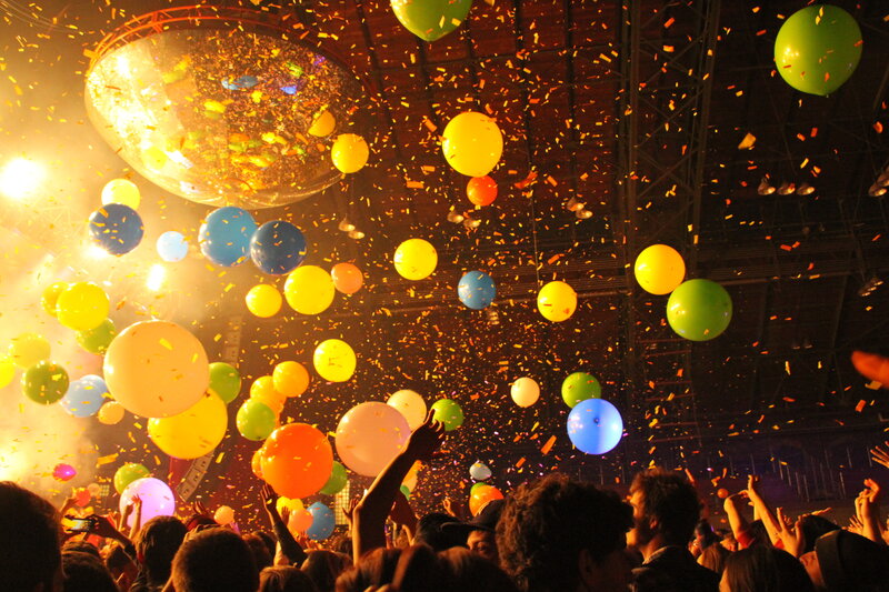 Crowd celebrating with balloons and confetti