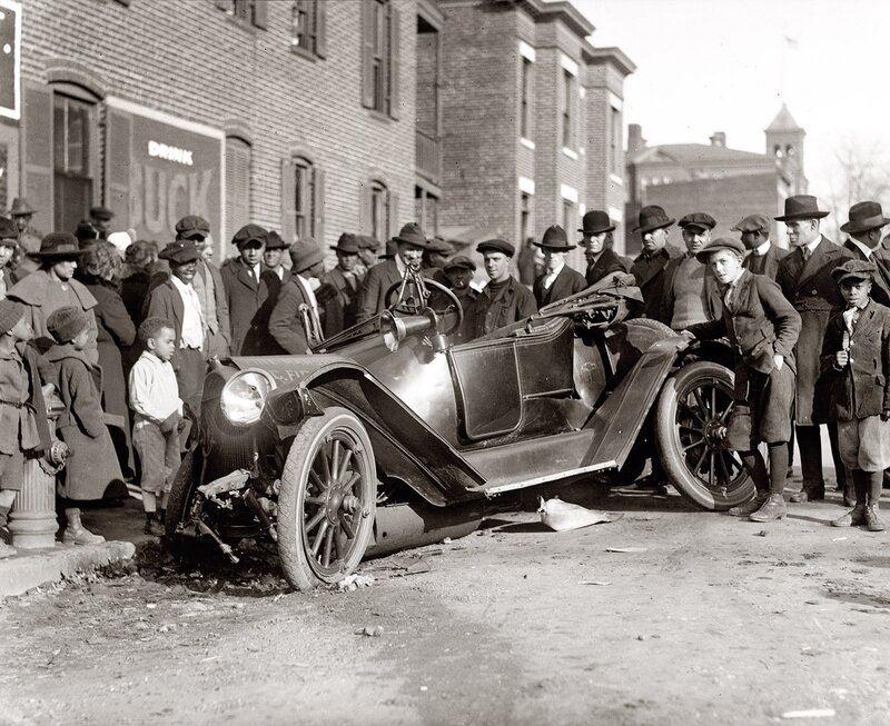Crowd gathers around damaged car
