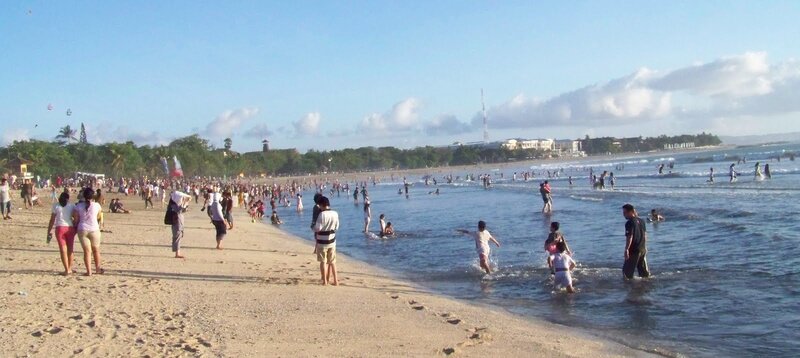Crowded beach with people swimming