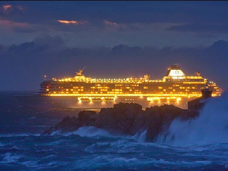Cruise ship at night near rocks