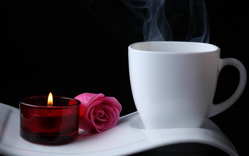 Cup of coffee with candle and rose