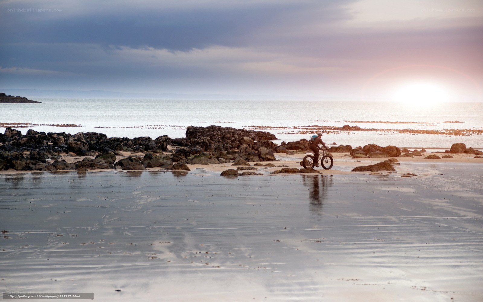 Cyclist on a rocky beach at sunset