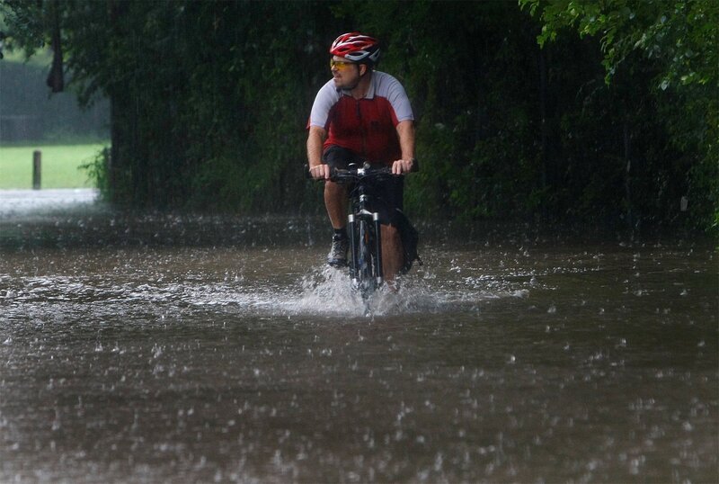 Cyclist rides through floodwaters