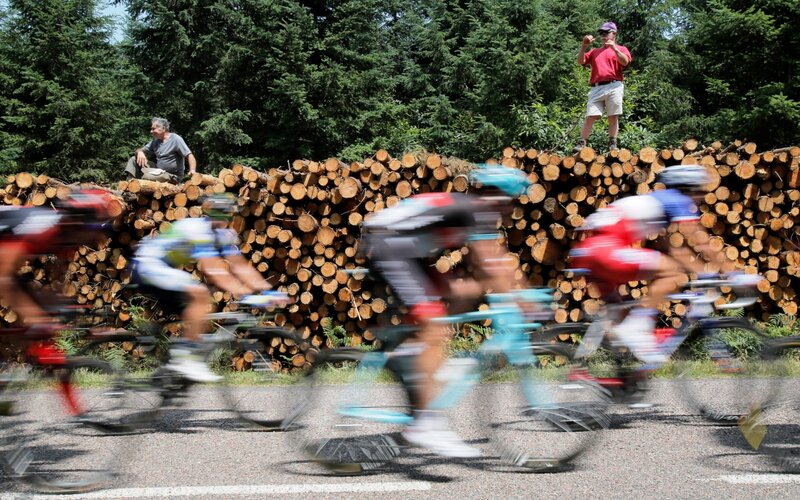 Cyclists racing past woodpile