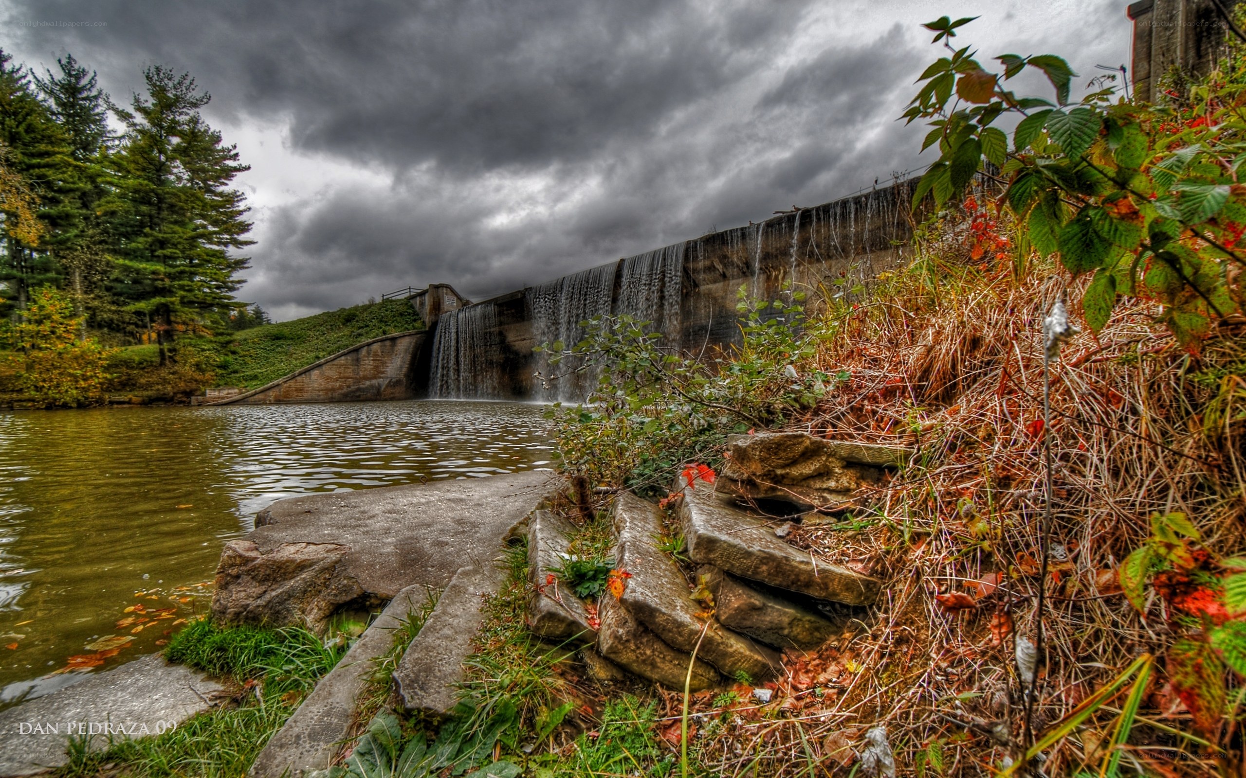 Dam with waterfall under stormy sky