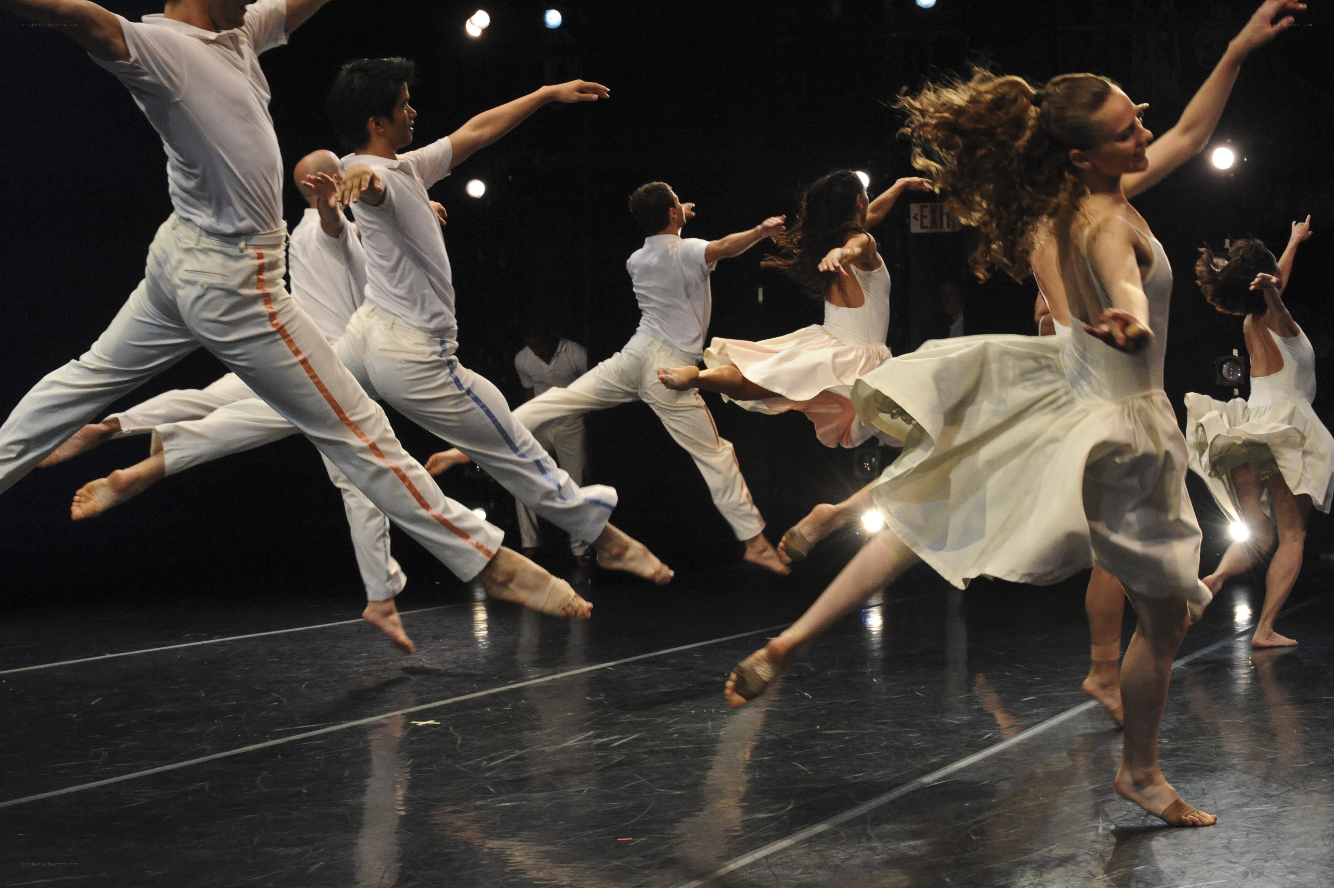 Dancers in white perform on stage