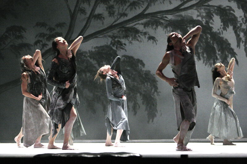 Dancers on a stage with tree backdrop