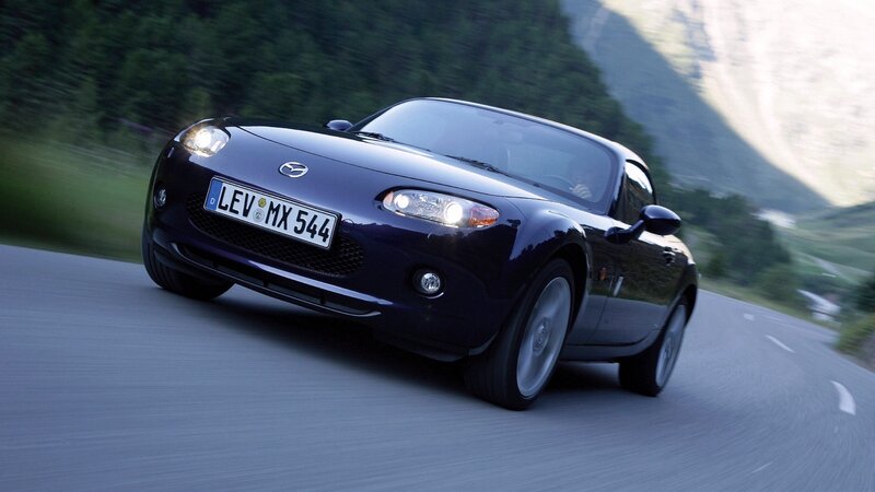Dark blue Mazda MX-5 driving on a road