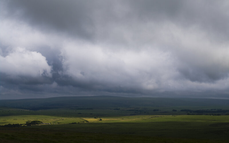 Dark clouds over green hills