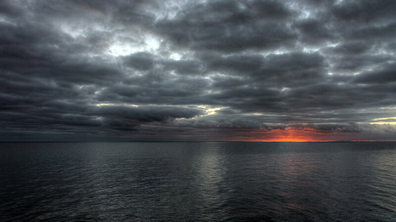 Dark clouds over ocean at sunset