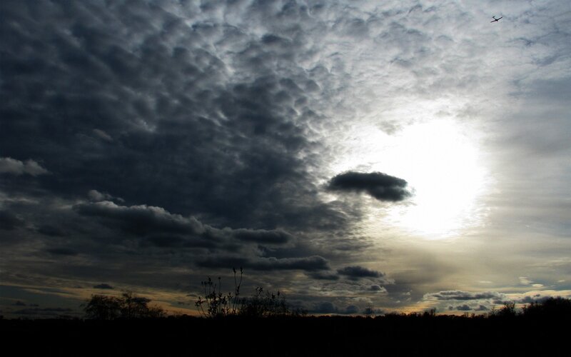 Dark clouds with sun and airplane