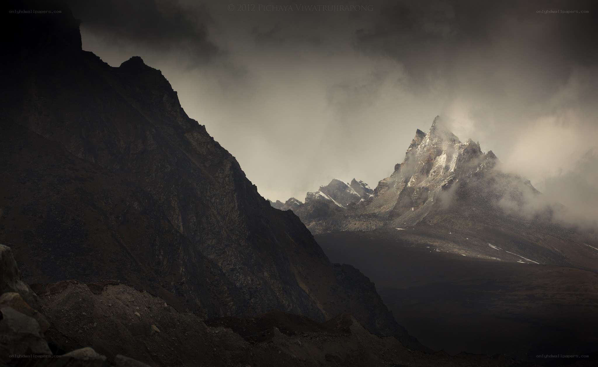 Dark mountain peaks under stormy sky