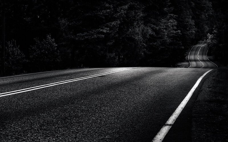 Dark road through forest at night