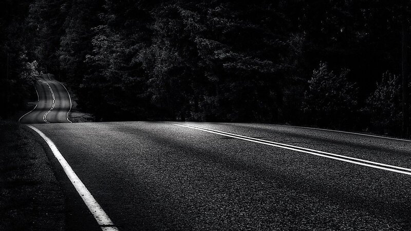 Dark road through forest