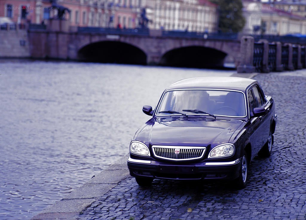 Dark sedan on cobblestone by river