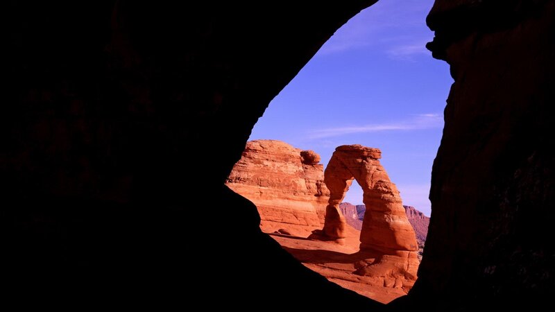 Delicate Arch Through Cave — Red, Dramatic