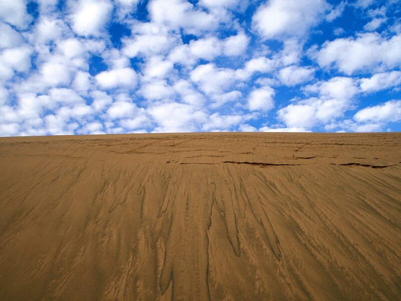 Desert dune under cloudy sky