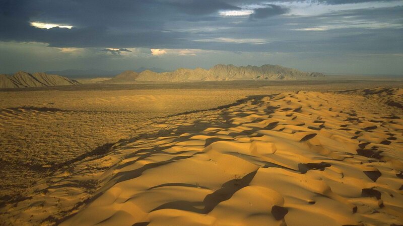 Desert dunes under stormy sky