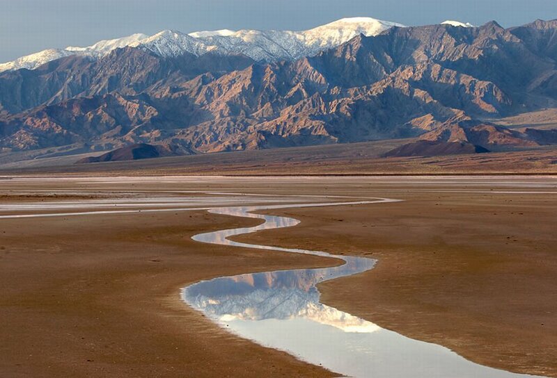 Desert river reflecting snow-capped mountains