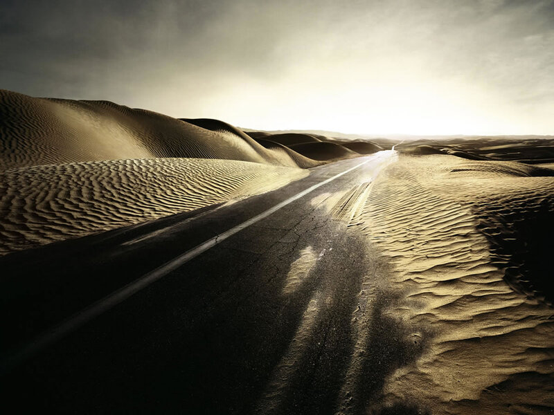 Desert road vanishing into dunes