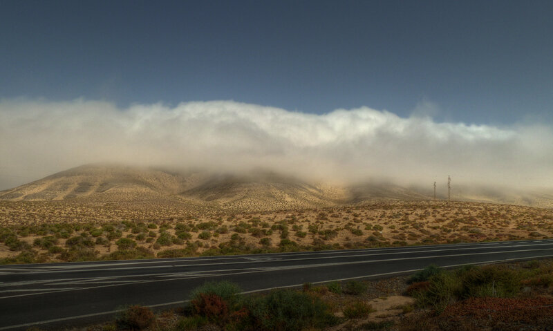 Desert road with cloud-covered hills