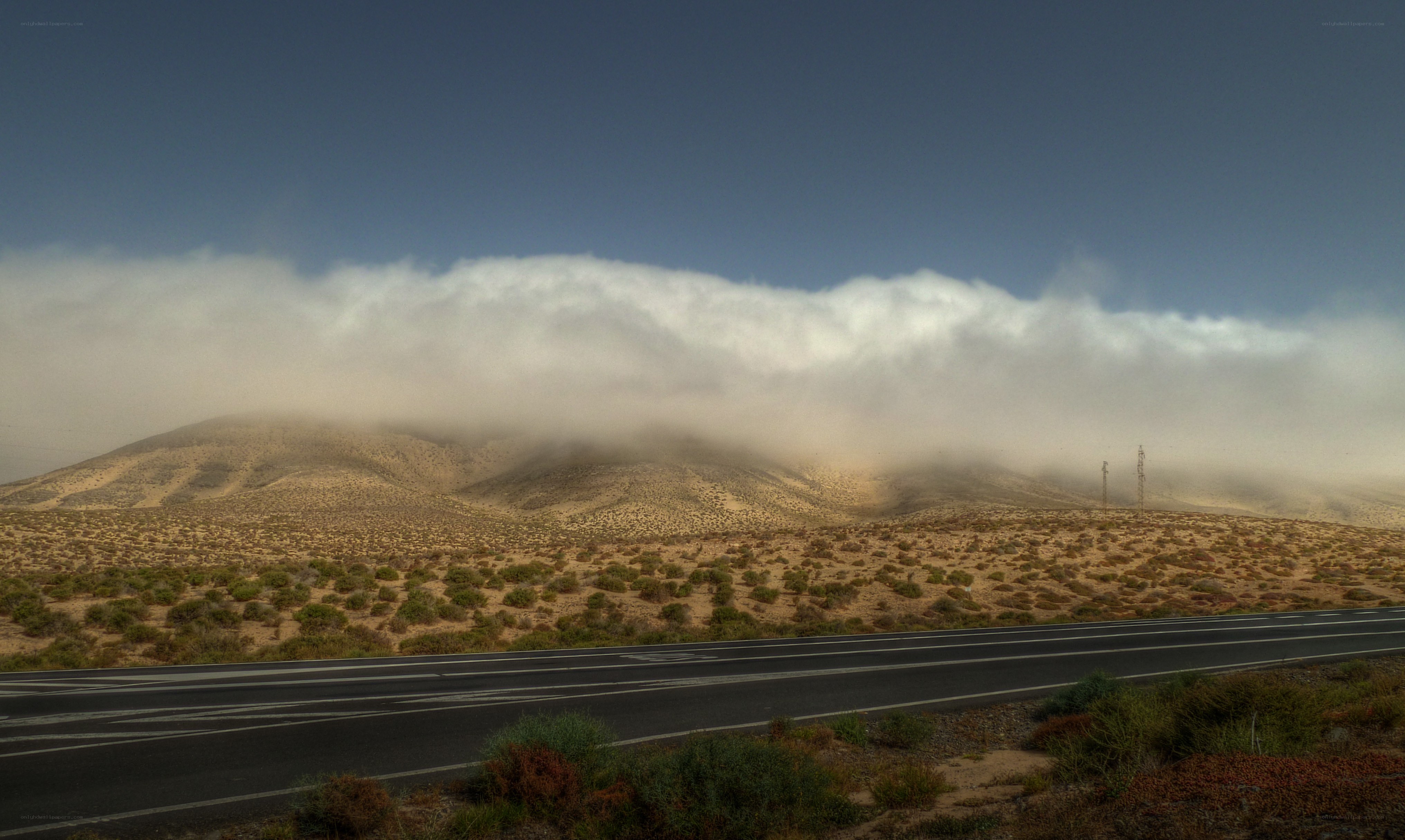 Desert road with cloud-covered hills