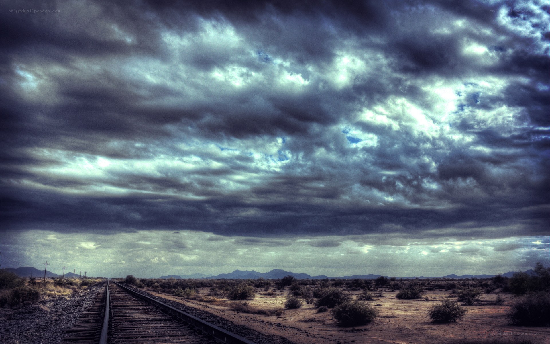 Desert train tracks under stormy sky