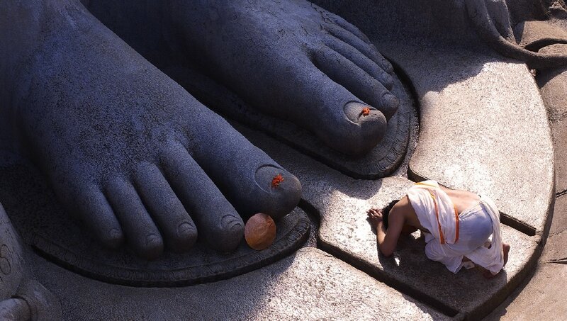 Devotee praying at statue feet