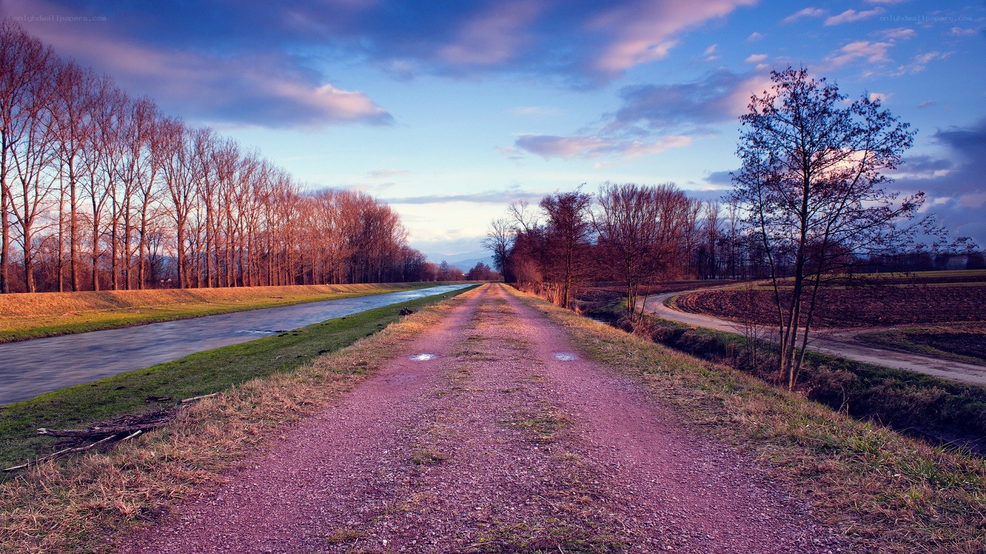 Dirt path by canal at dusk