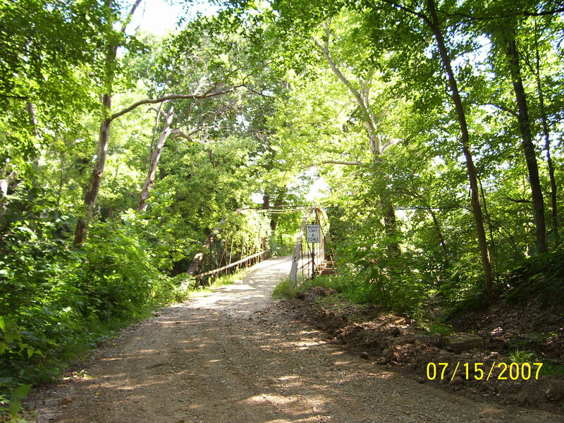 Dirt path through forest to bridge