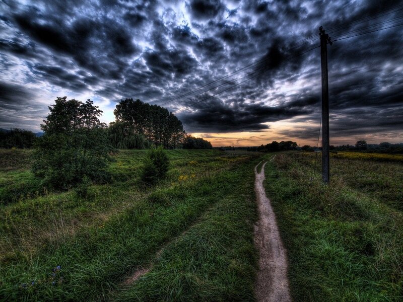 Dirt path under stormy sky